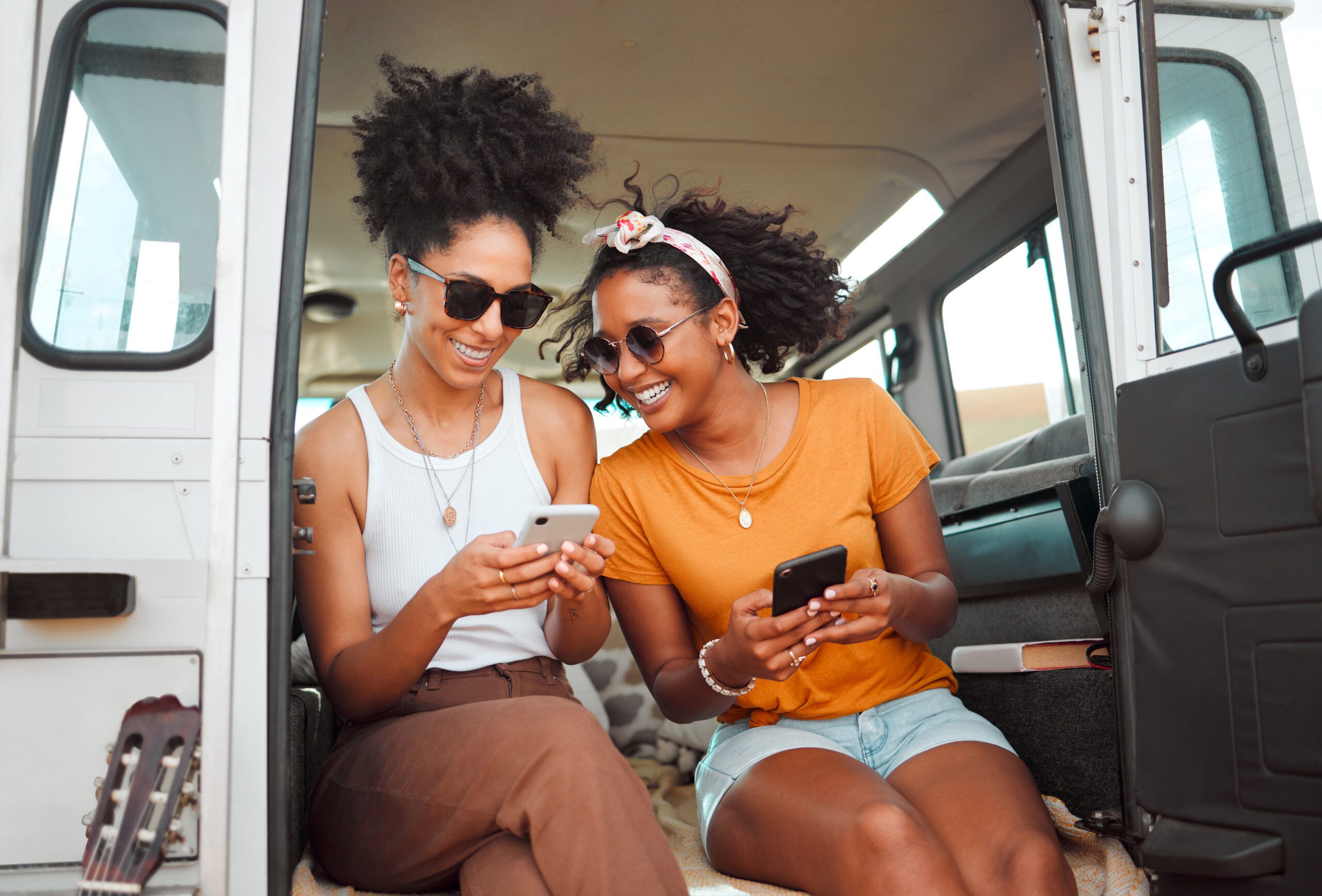 Women, road trip or phone for social media, gps location or map app for safari game drive or summer travel. Smile, happy or bonding friends with 5g mobile technology in camper van in nature landscape