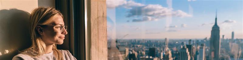 Woman looking at the city through the window